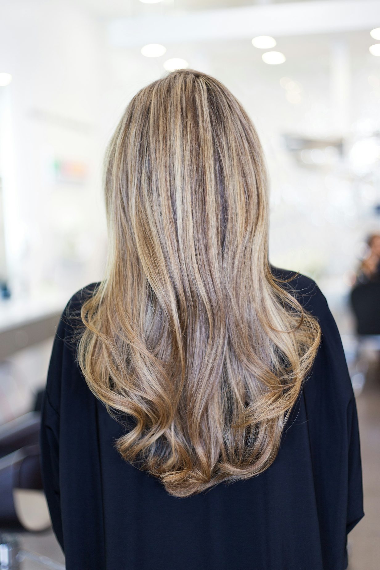Lang golvend haar met warme blonde balayage highlights, gefotografeerd in een kapsalon