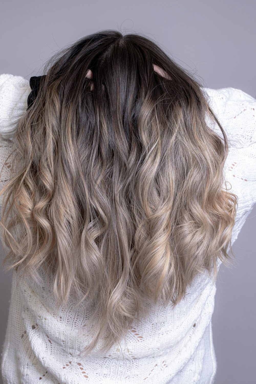 Golvend haar met een zachte balayage overgang van donkere wortels naar blonde highlights