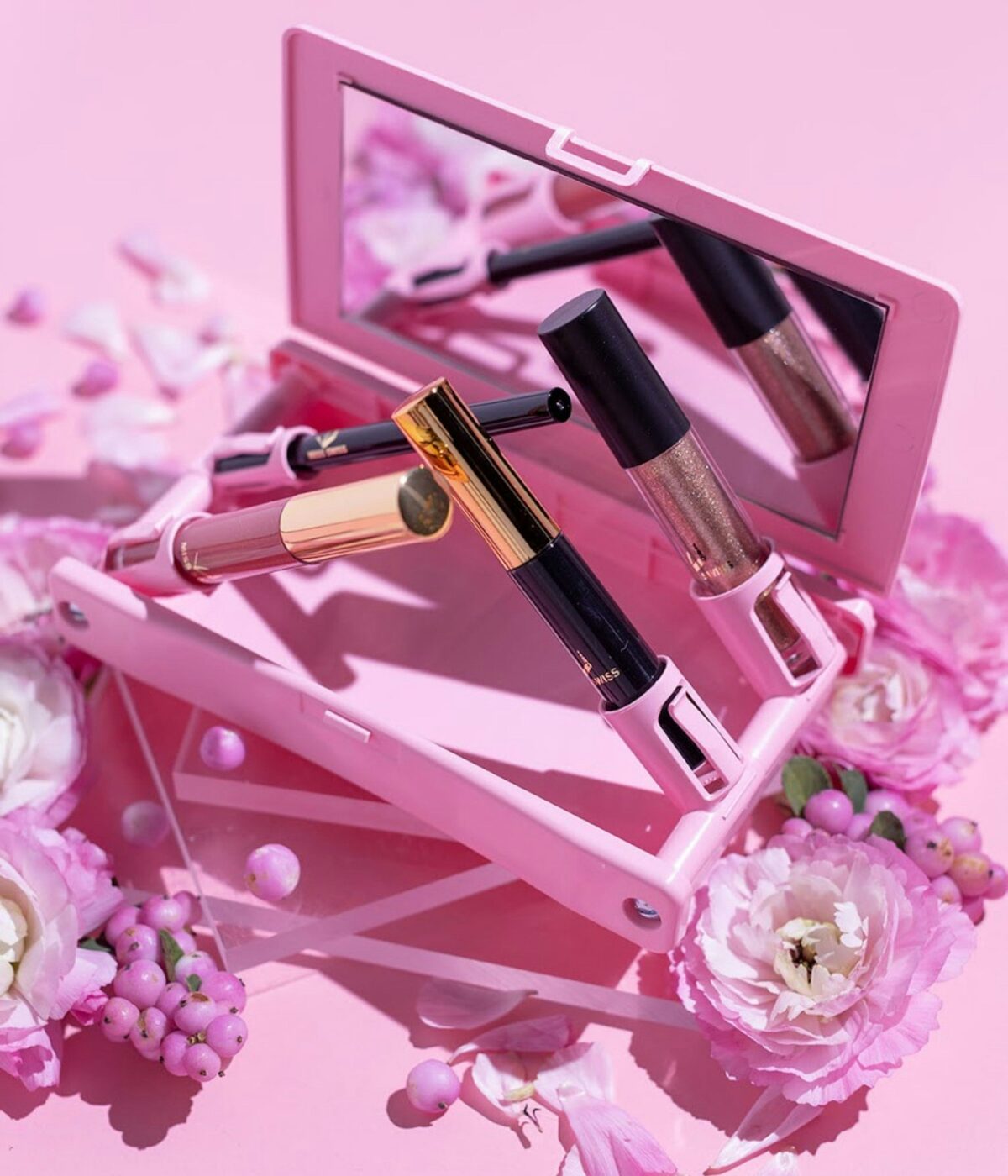 Roze flatlay met lipgloss, een spiegel en bloemen, klaar voor social content