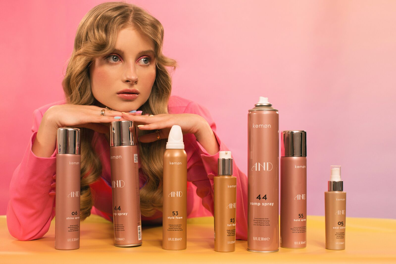 Beauty model poseert bij een fotoshoot tussen roze haarstylingproducten