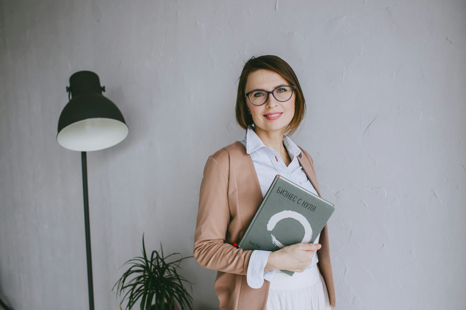 Zelfverzekerde beauty-ondernemer met bril houdt een map met haar businessplan vast