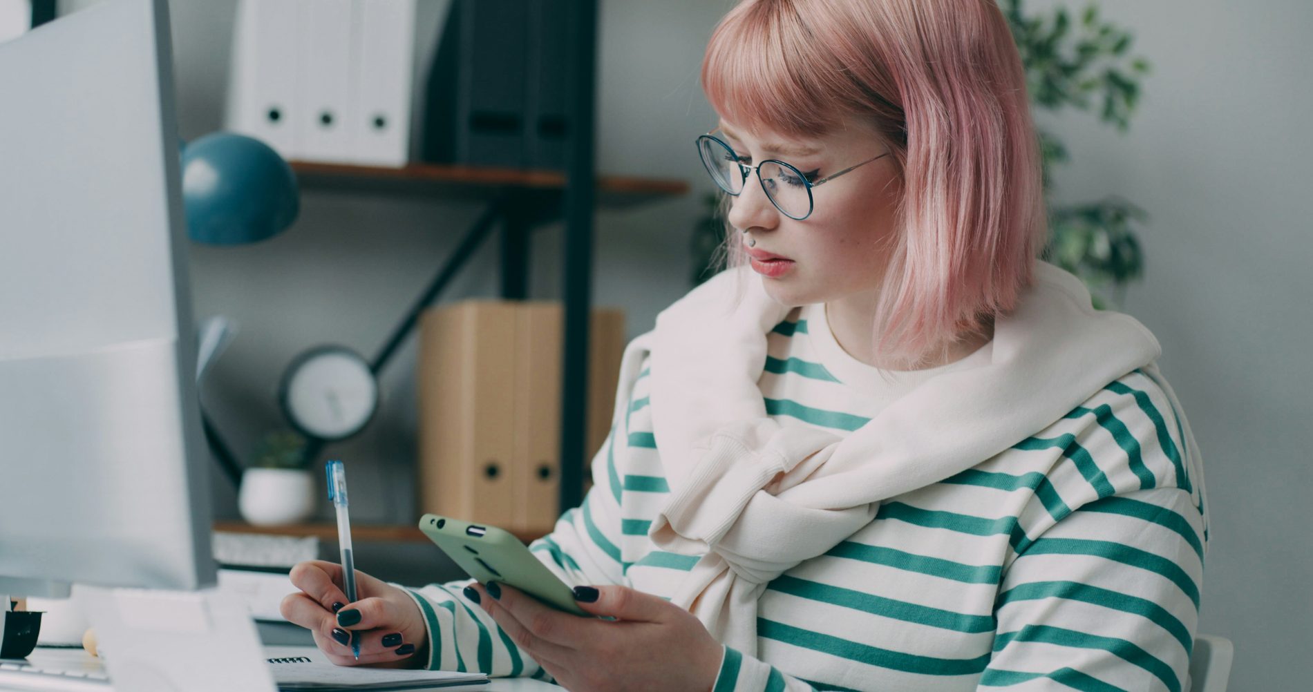 Beauty-ondernemer berekent haar kosten met een telefoon, pen en notitieblok aan een bureau