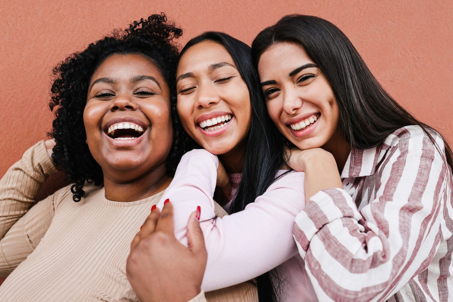 Drie vrolijke beauty-ondernemers dicht bij elkaar, lachend, als teken van verbinding