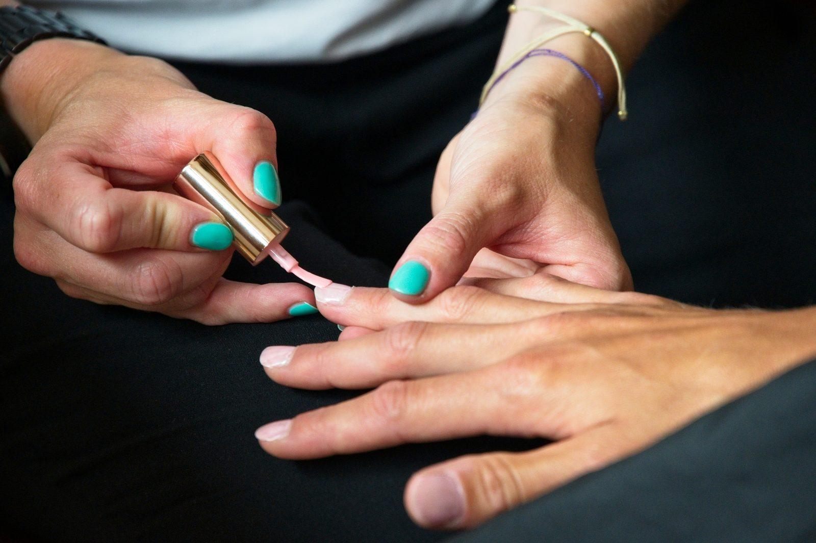 Nagelstyliste brengt een dunne laag gellak aan op de nagel van een klant