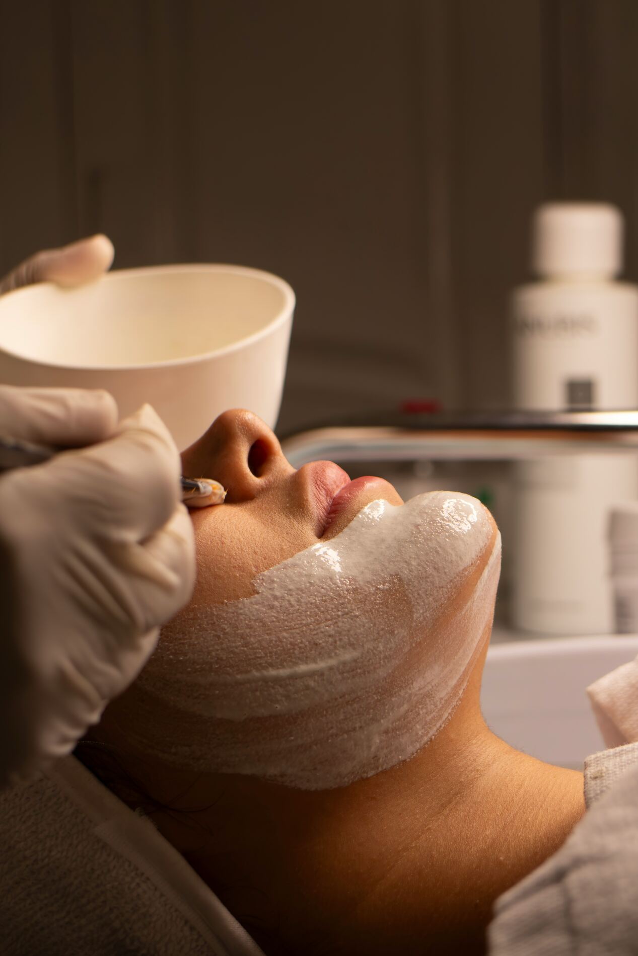 Gezichtsbehandeling met een schuimend masker in de salon, cliënt ligt ontspannen achterover