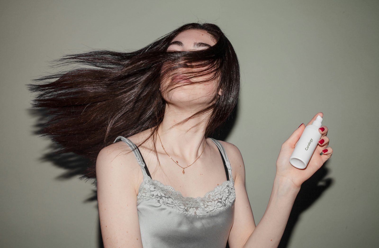 Vrouw houdt een fles haarverzorgingsproduct vast terwijl ze haar haar naar achteren gooit