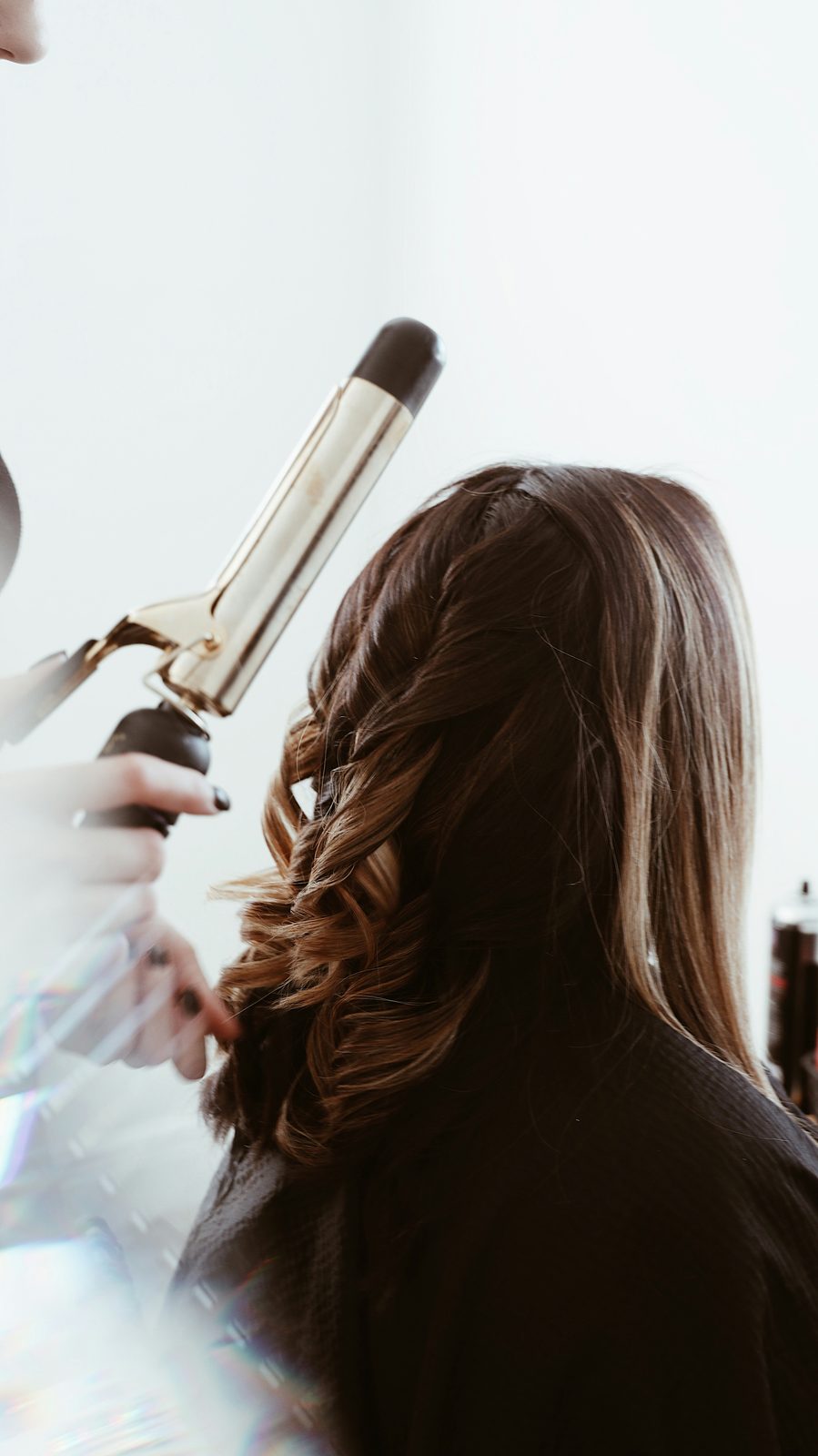 Kapster krult het haar van een klant met een krultang in de salon
