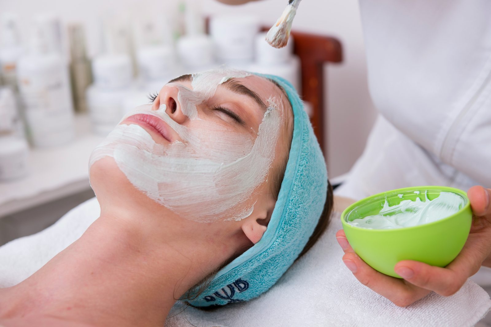 Huidspecialist brengt een masker aan tijdens een gezichtsbehandeling in de salon