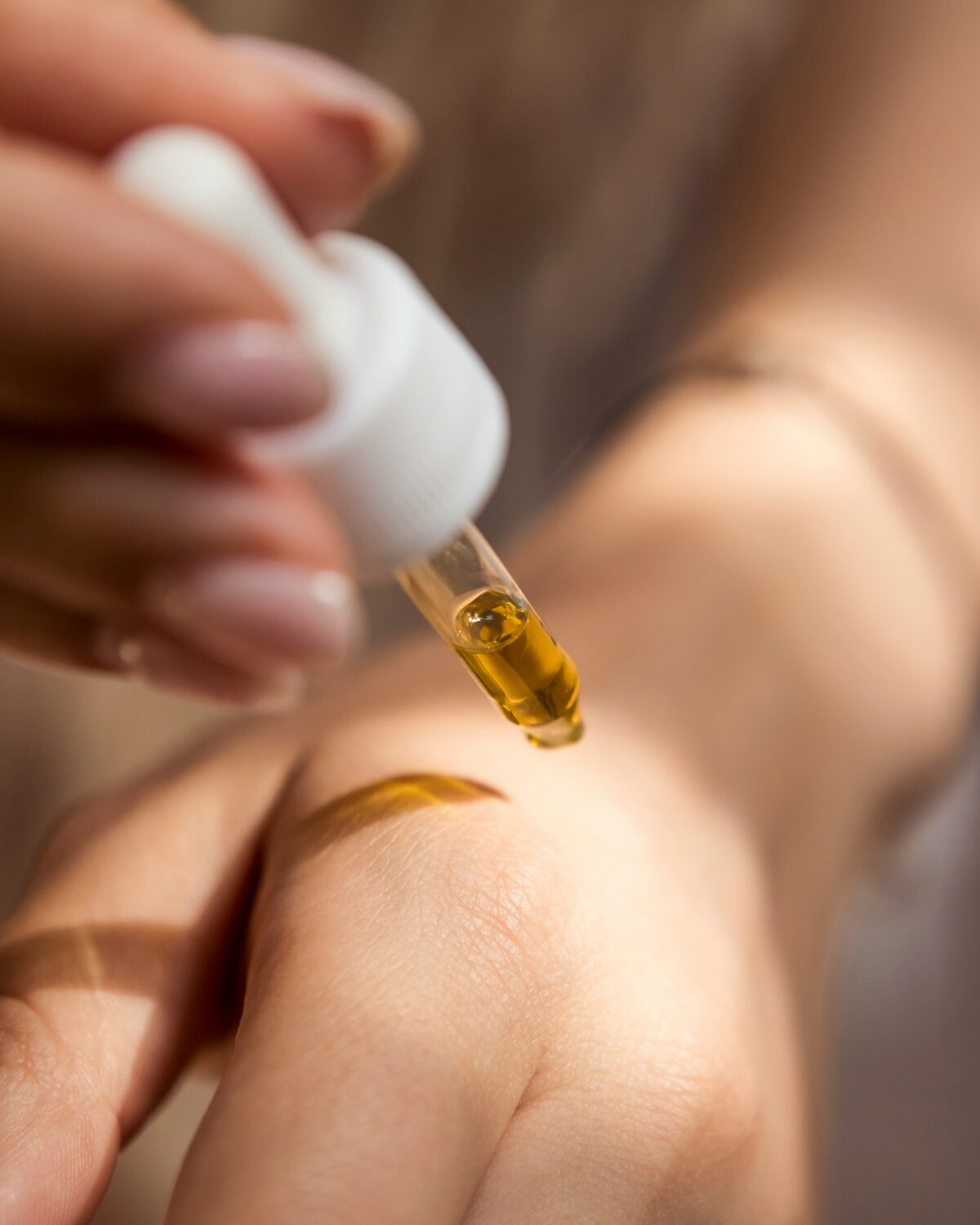 Hand brengt met een pipet een serum aan op de huid