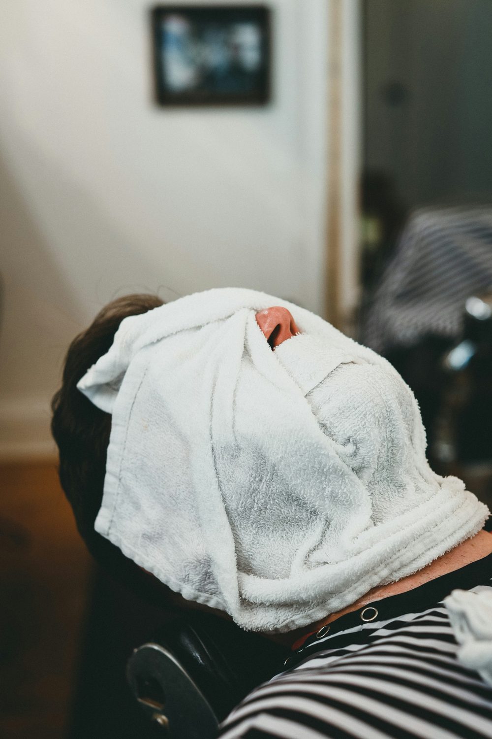 Klant ontspant met het hoofd in een handdoek gewikkeld na een gezichtsbehandeling in de salon