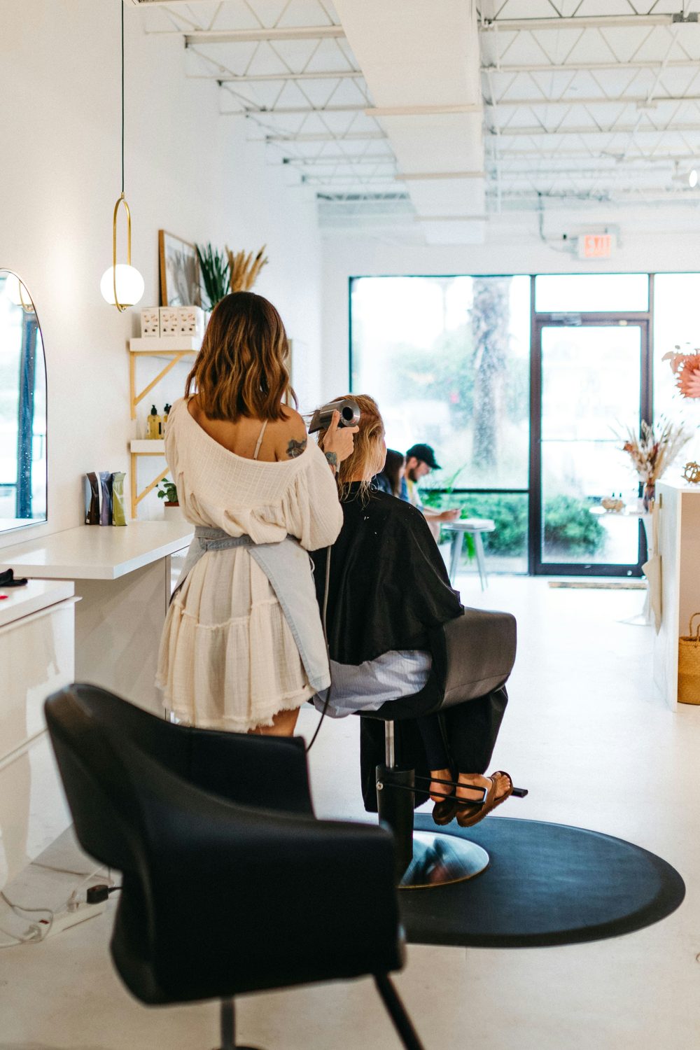 Kapster föhnt het haar van een klant en werkt geconcentreerd in een lichte salon