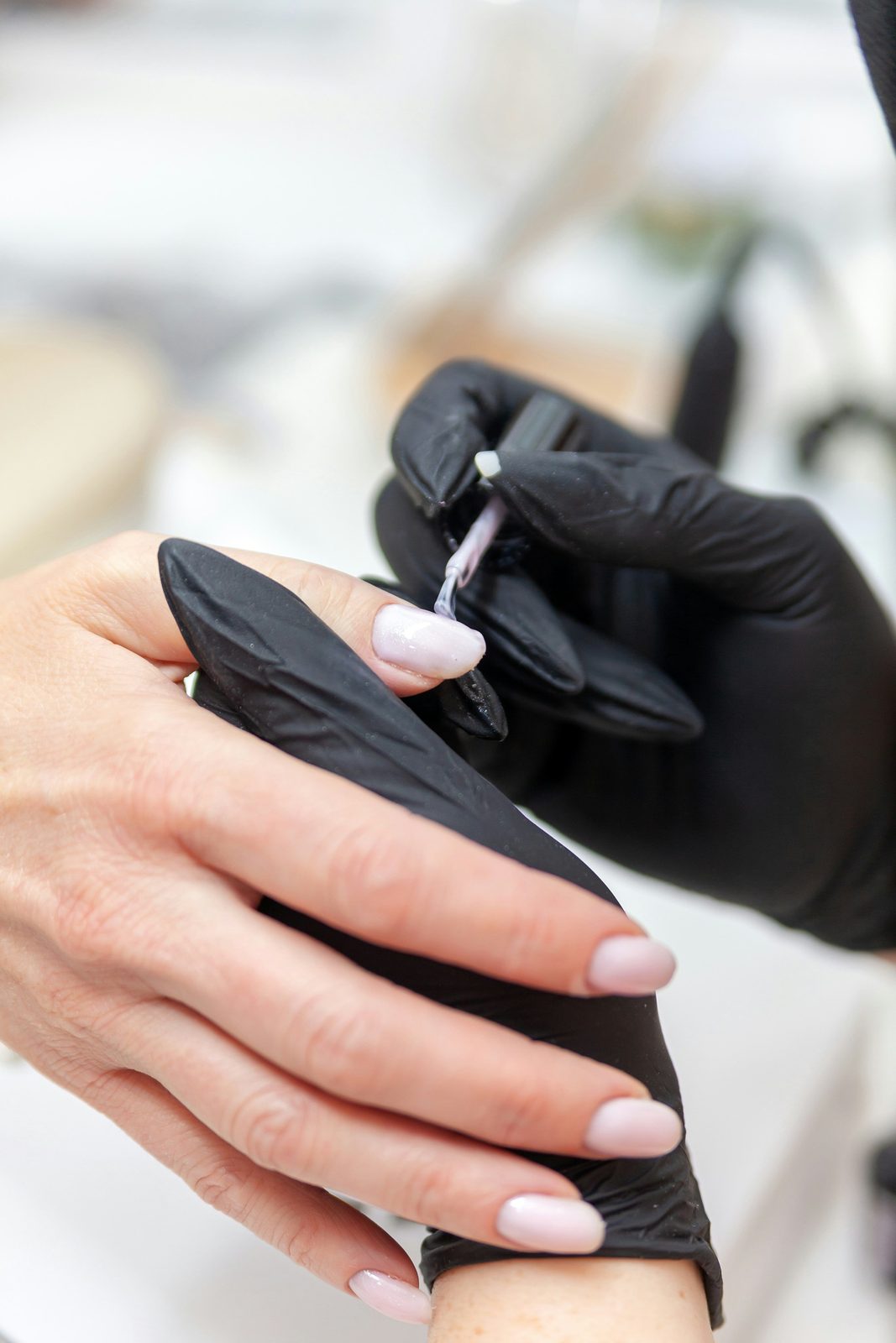 Nagelstyliste brengt gel aan tijdens een behandeling