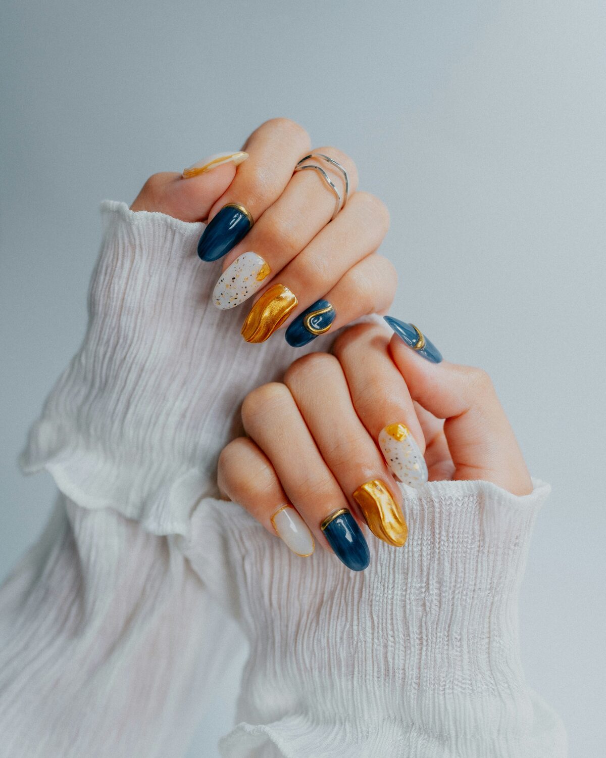 Hand met kleurrijke nail art in blauw en goud op een BIAB-basis