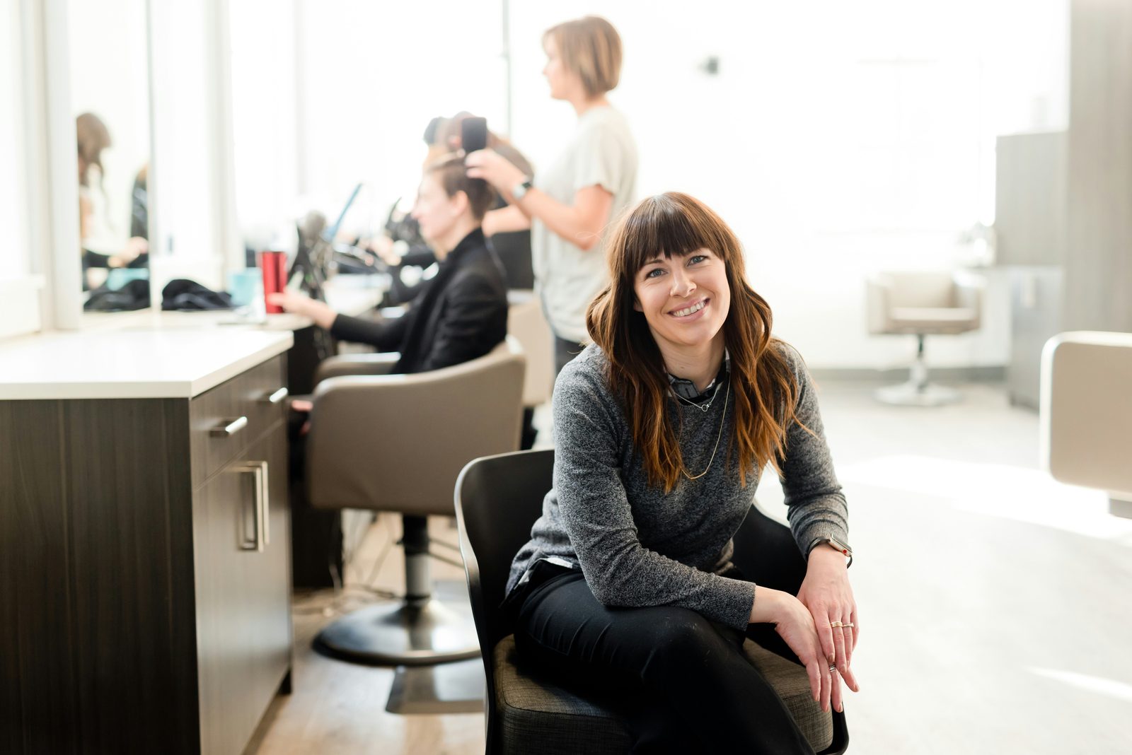 Lachende salon-eigenaar in haar lichte schoonheidssalon