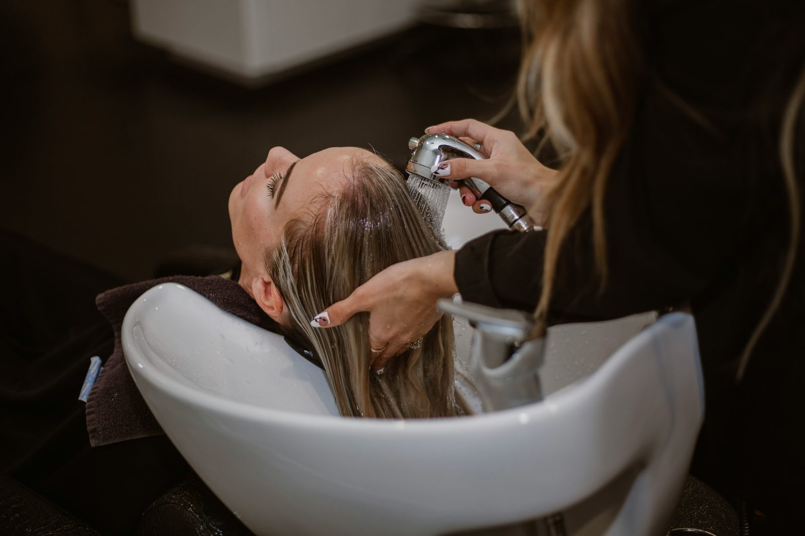 Kapster wast het haar van een klant bij de wasbak in de salon