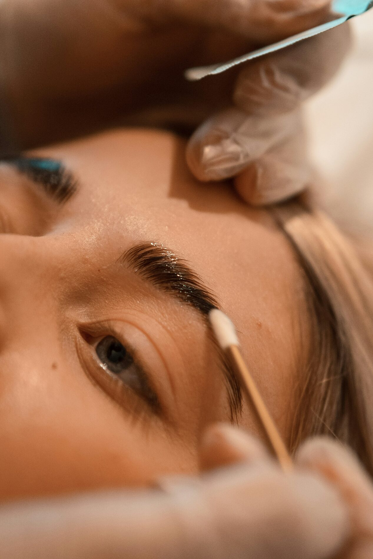 Close-up van een wenkbrauwbehandeling in de salon, waarbij de wenkbrauw wordt bijgewerkt met een wattenstaafje