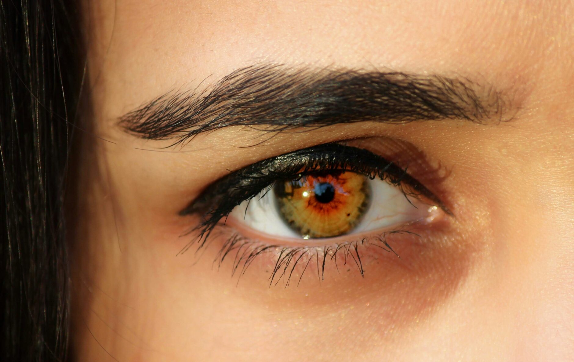 Extreme close-up van een oog met een volle, donkere wenkbrauw en zwarte eyeliner