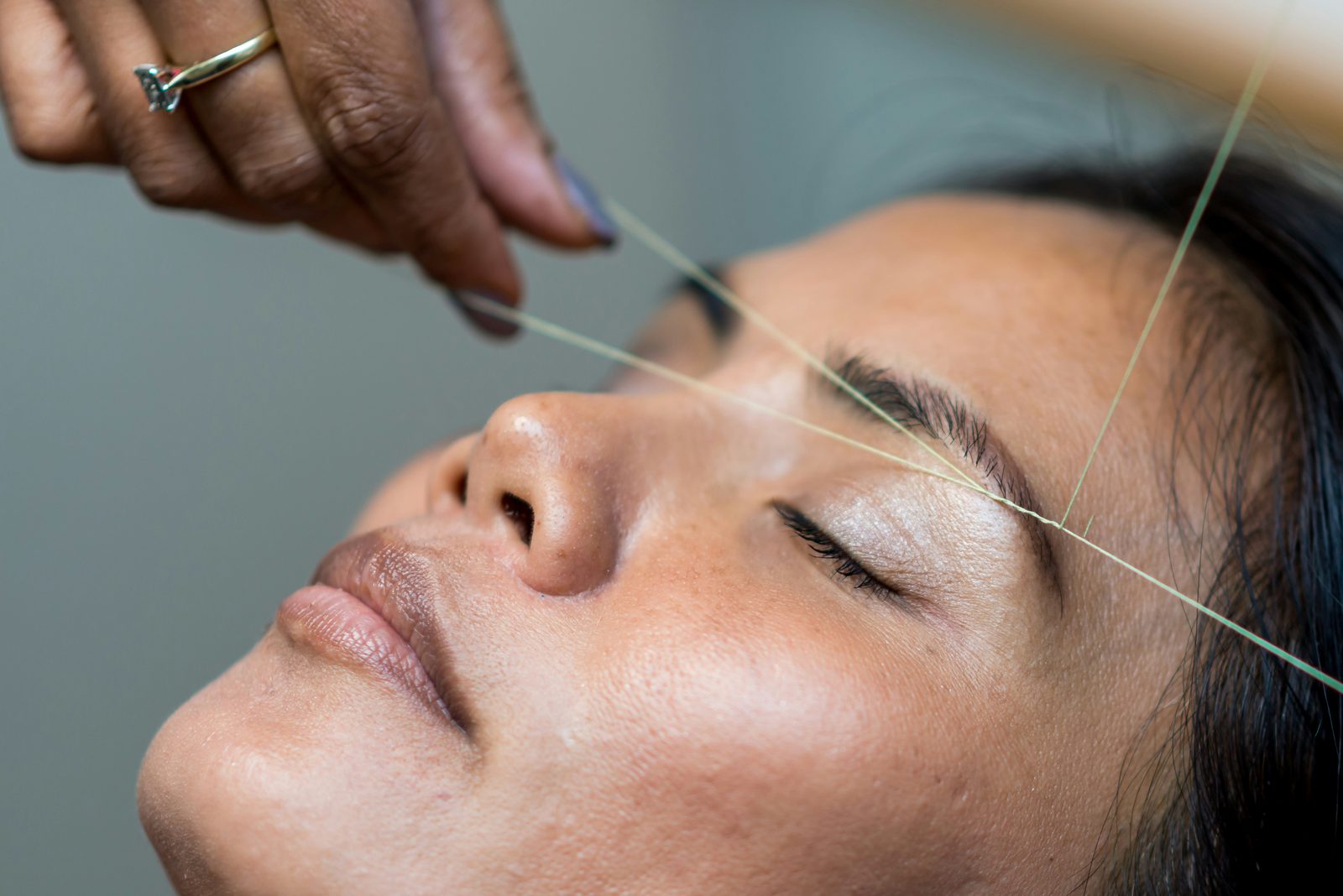 Specialist geeft de wenkbrauwen vorm met de threading-techniek