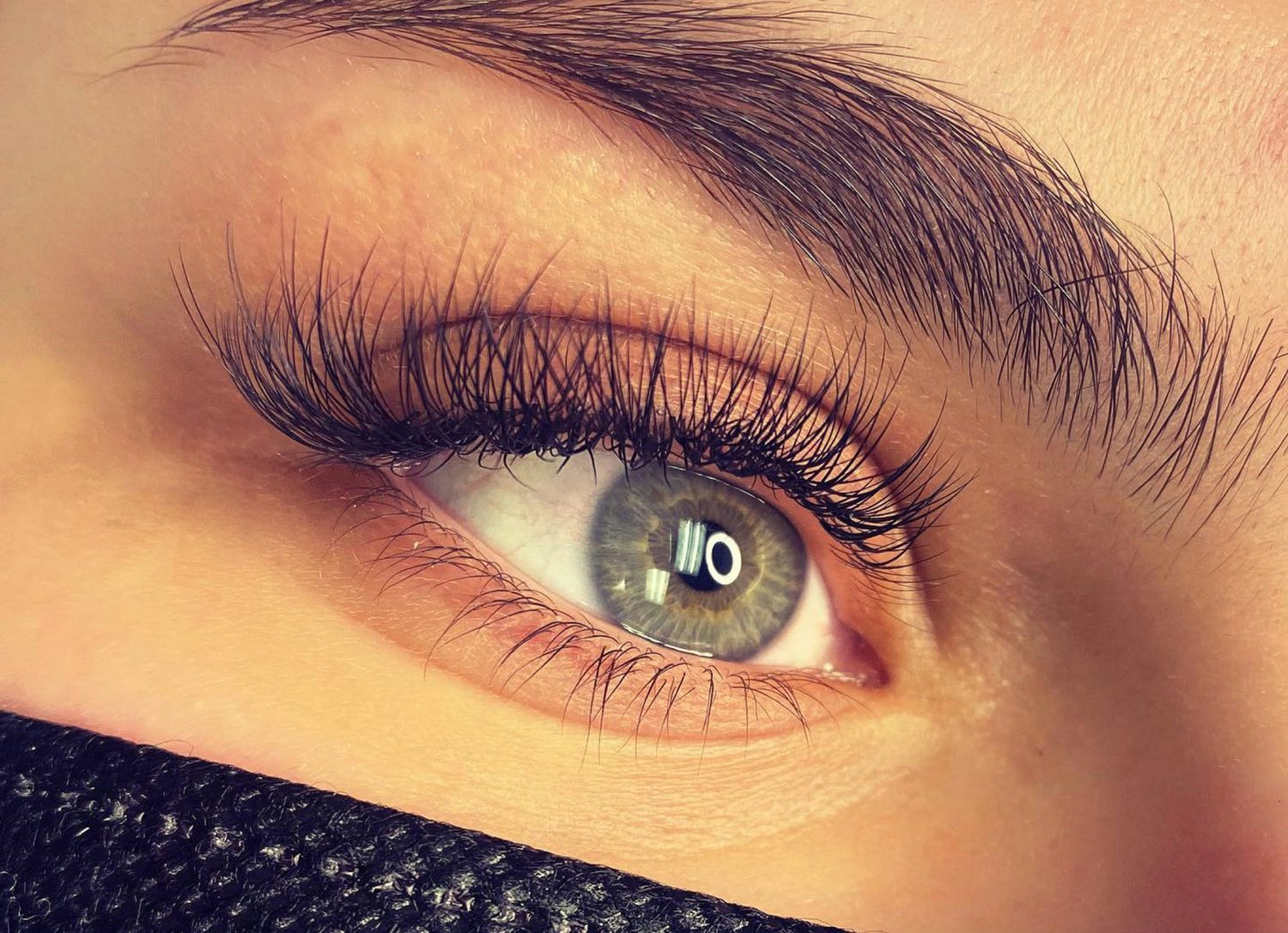 Close-up van een oog met een volledige set volle wimperextensions als eindresultaat van een behandeling