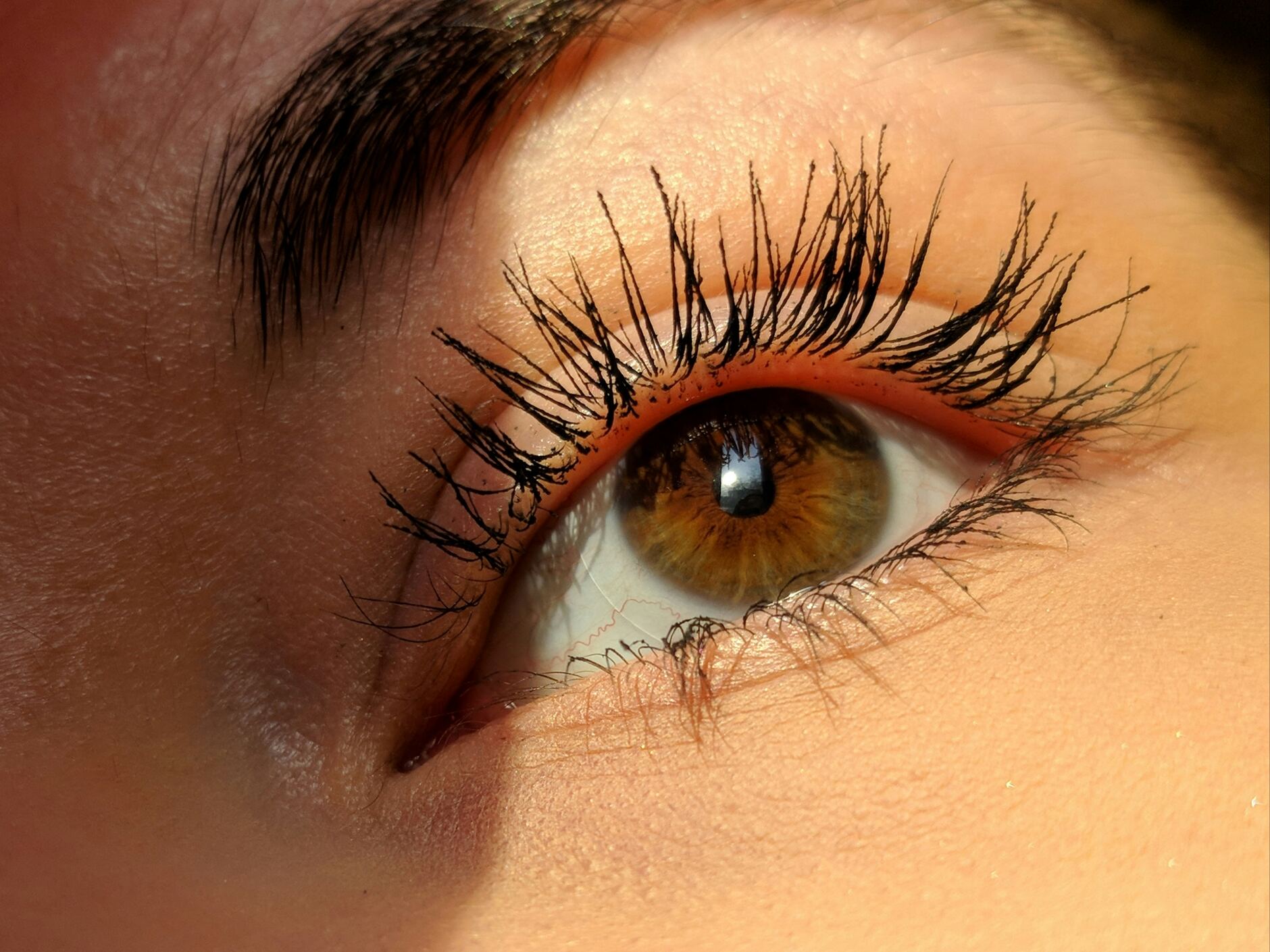 Close-up van een oog met lange, gekrulde donkere wimperextensions