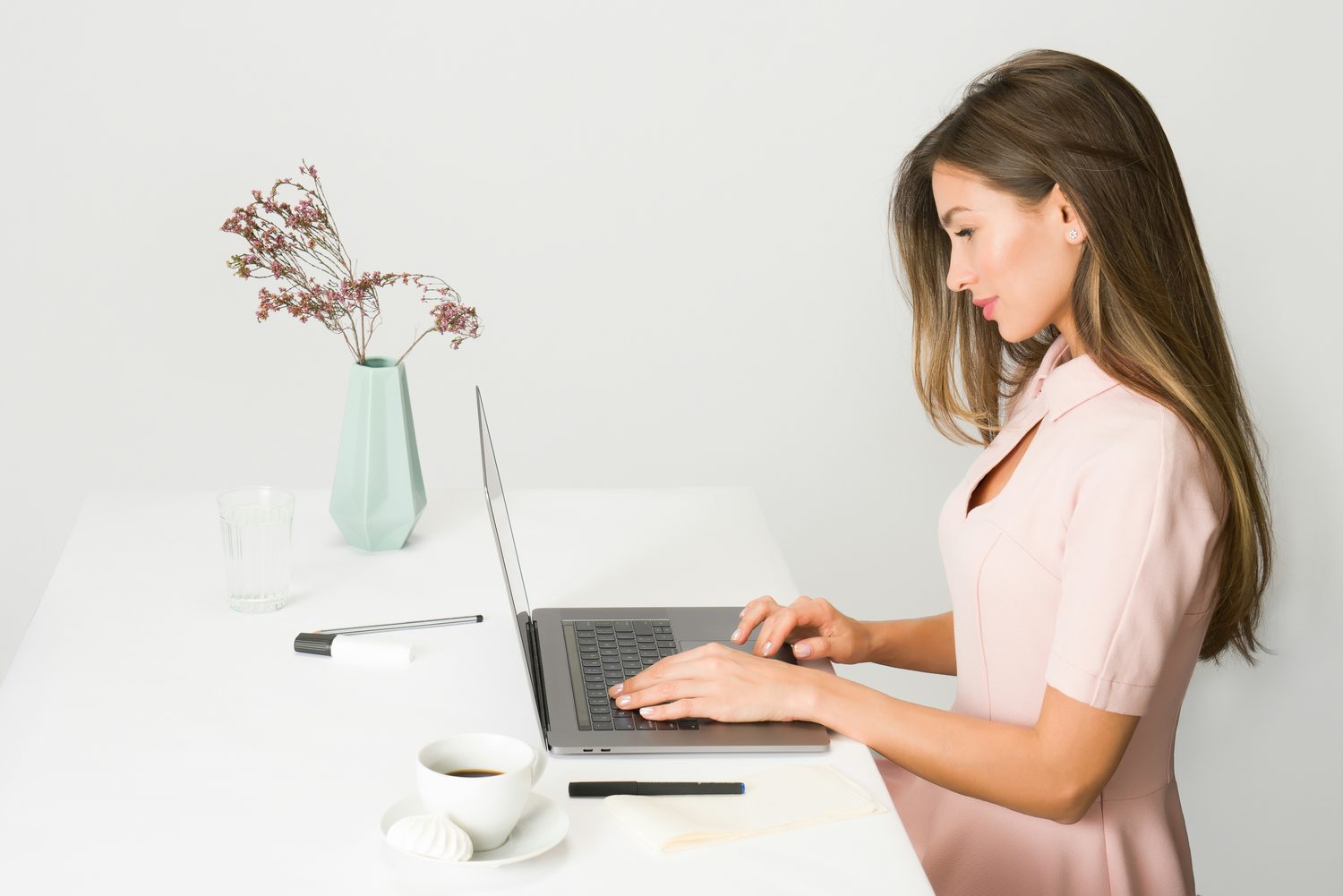 Vrouw beheert haar agenda en boekingssysteem op een laptop aan een bureau